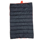 A black puffer sleeping pad with bright orange trim and a top carry loop, laid flat on a light wood floor.